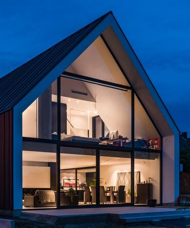 Private house with glass façade, lots of lights by night.