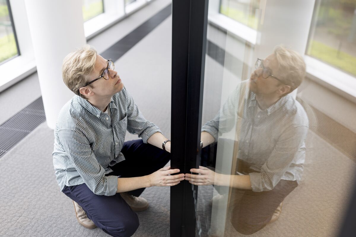 Man with glasses holding black aluminium profile.