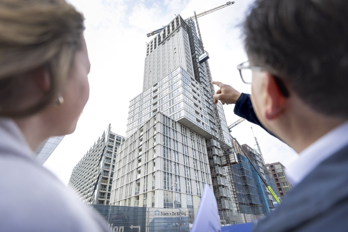 Man and woman looking up at grey high-rise building under construction.