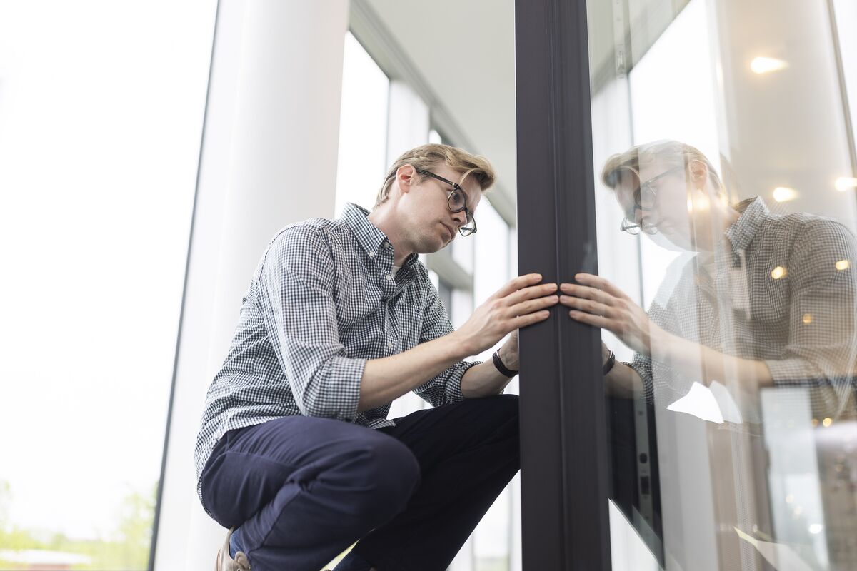 Man with glasses looking attentively at black aluminium profile in showroom.