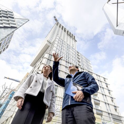 Man and woman pointing at and talking about high-rise buildings.