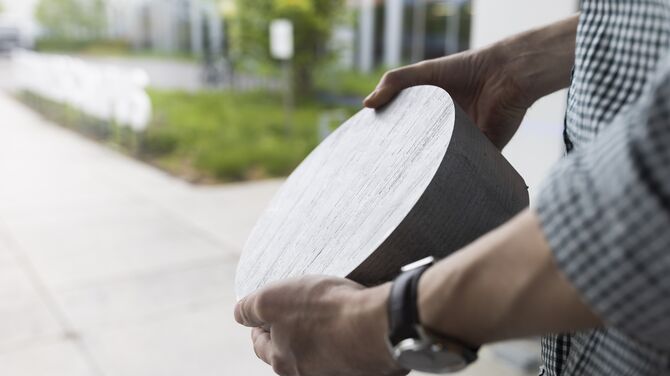 Man holding aluminium billet sample.