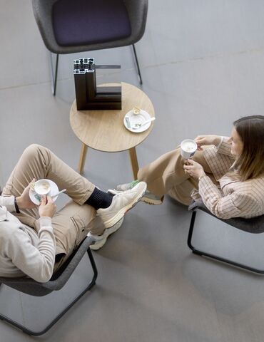 Top view of man and woman sitting at a table, drinking coffee.