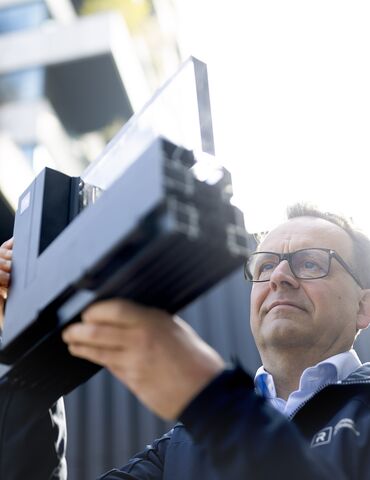 Man with glasses looking closely at aluminium corner sample.