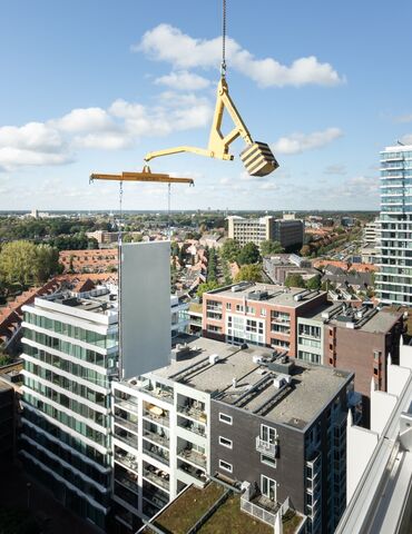 Modular building panel lifted next to skyscraper.