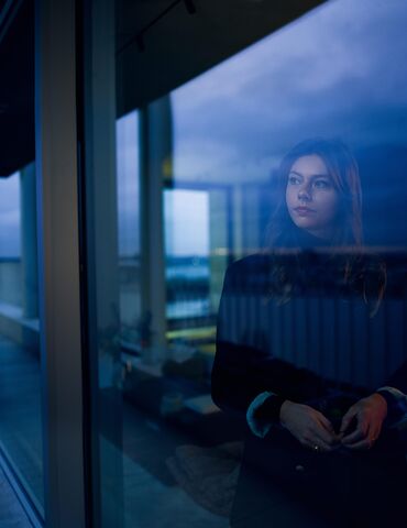 Woman looking out of window at nightfall.