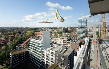 Modular building panel lifted next to skyscraper.