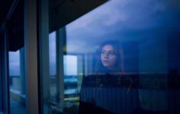 Woman looking out of window at nightfall.